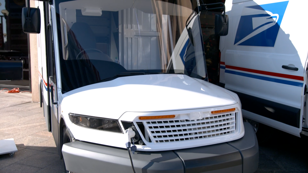 Front view of Electric USPS delivery van being charged